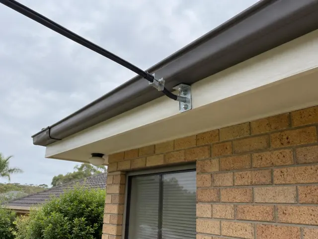 Overhead service cable and new attachment bracket on a brick house exterior in Narara